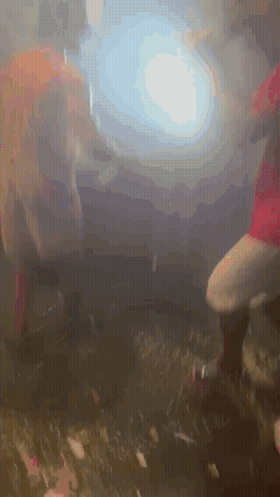 A Group Of People Are Dancing In A Dark Room With Smoke Coming Out Of The Ceiling . GIF
