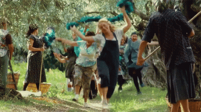 A Group Of People Are Dancing In A Field And One Woman Is Wearing Overalls GIF