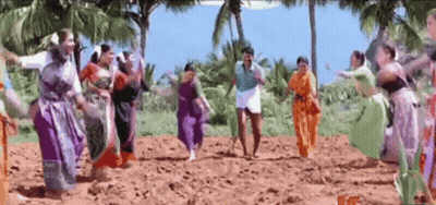 A Group Of People Are Dancing In A Field With A Man In A Blue Shirt GIF