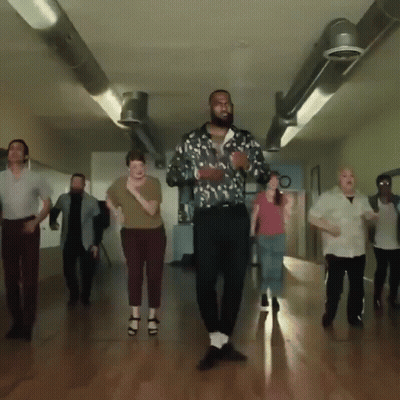 A Group Of People Are Dancing In A Hallway With A Man Wearing A Floral Shirt GIF