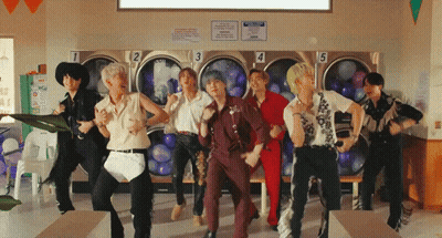 A Group Of People Are Dancing In A Laundromat With Numbers 1 2 3 4 And 5 On The Washers GIF