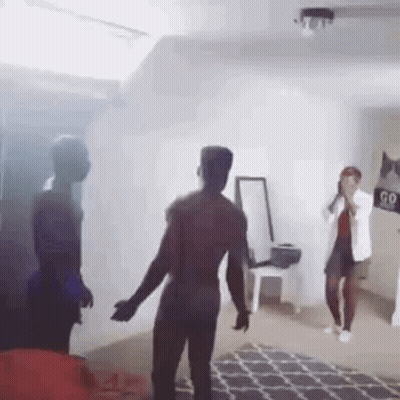 A Group Of People Are Dancing In A Living Room With Smoke Coming Out Of The Window . GIF