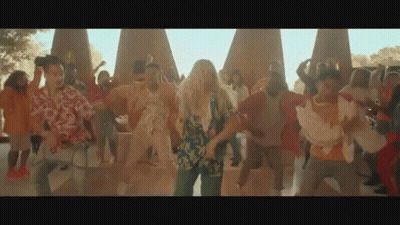 A Group Of People Are Dancing In A Park In Front Of A Large Group Of People . GIF