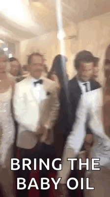 A Group Of People Are Dancing In A Room And One Of Them Is Holding A Baby Oil Bottle . GIF