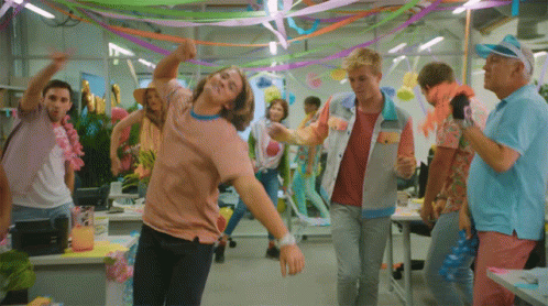 A Group Of People Are Dancing In A Room Decorated With Colorful Ribbons GIF