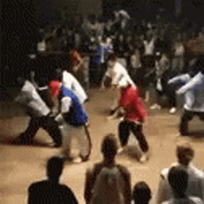 A Group Of People Are Dancing In A Room While A Crowd Watches . GIF