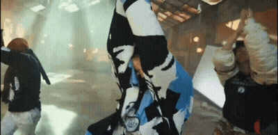 A Group Of People Are Dancing In A Room While A Man Is Holding A Flag . GIF