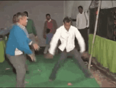 A Group Of People Are Dancing In A Room With A Green Curtain Behind Them GIF