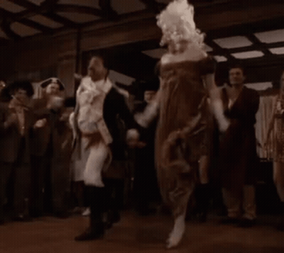 A Group Of People Are Dancing In A Room With A Woman In A Dress . GIF