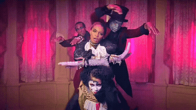 A Group Of People Are Dancing In A Room With Pink Curtains And A Woman In A Top Hat . GIF