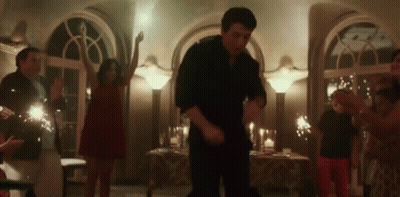 A Group Of People Are Dancing In A Room With Sparklers In The Background . GIF