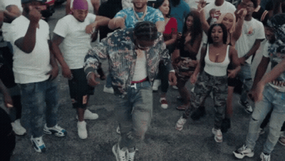 A Group Of People Are Dancing In A Street With A Man Wearing A Floral Jacket GIF