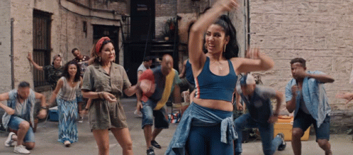 A Group Of People Are Dancing In An Alleyway In Front Of A Brick Building GIF