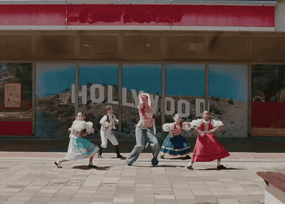A Group Of People Are Dancing In Front Of A Building That Says Hollywood GIF