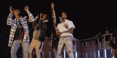 A Group Of People Are Dancing In Front Of A Building With The Letter S On The Front GIF