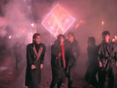 A Group Of People Are Dancing In Front Of A Glowing Sign . GIF
