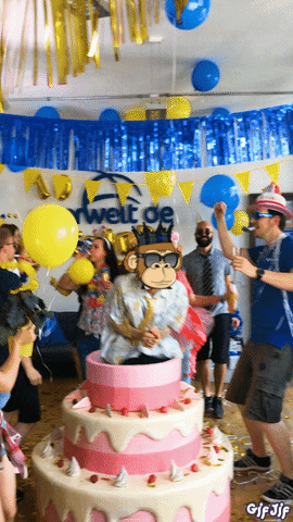 A Group Of People Are Dancing In Front Of A Large Cake With A Monkey On It GIF