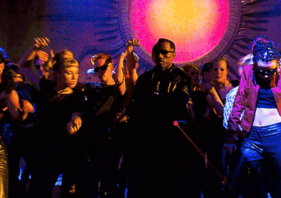 A Group Of People Are Dancing In Front Of A Large Pink Light GIF