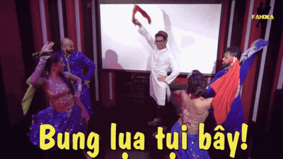 A Group Of People Are Dancing In Front Of A Large Screen That Says Bung Lua Tui Bay GIF