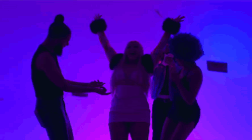 A Group Of People Are Dancing In Front Of A Purple Background While A Woman Throws Money In The Air . GIF