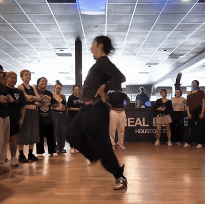A Group Of People Are Dancing In Front Of A Real Houston Sign GIF