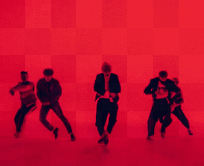 A Group Of People Are Dancing In Front Of A Red Background . GIF