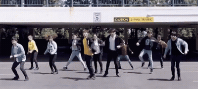 A Group Of People Are Dancing In Front Of A Sign That Says " Caution 2 Way Traffic " GIF