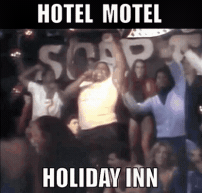 A Group Of People Are Dancing In Front Of A Sign That Says " Hotel Motel Holiday Inn " GIF