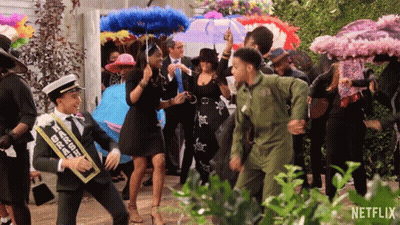 A Group Of People Are Dancing In Front Of A Sign That Says Netflix On It GIF