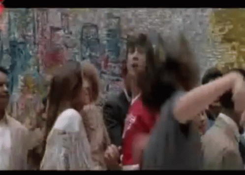 A Group Of People Are Dancing In Front Of A Wall With Graffiti . GIF