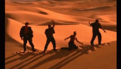 A Group Of People Are Dancing In The Desert . GIF