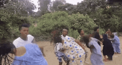 A Group Of People Are Dancing In The Dirt In A Field . GIF