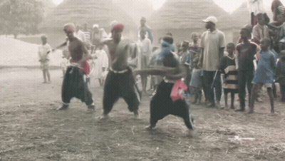 A Group Of People Are Dancing In The Dirt In Front Of A Crowd GIF