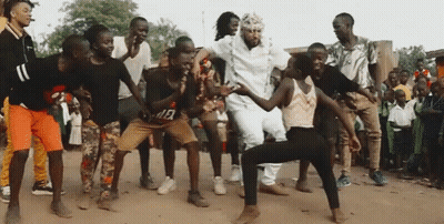 A Group Of People Are Dancing In The Dirt In Front Of A Crowd Of People . GIF