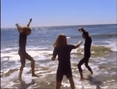 A Group Of People Are Dancing In The Water On A Beach GIF