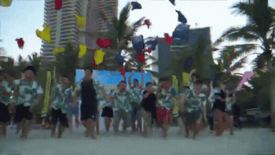 A Group Of People Are Dancing On A Beach With Balloons In The Air GIF