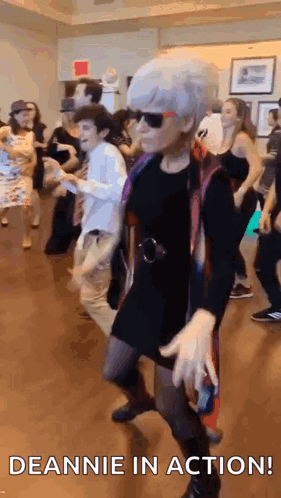 A Group Of People Are Dancing On A Dance Floor And The Woman Is Wearing Sunglasses . GIF