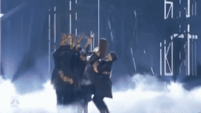 A Group Of People Are Dancing On A Stage In A Dark Room . GIF