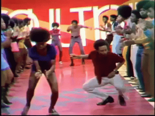 A Group Of People Are Dancing On A Stage In Front Of A Sign That Says " Out " GIF