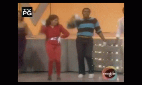 A Group Of People Are Dancing On A Stage In Front Of A Yellow Wall . GIF