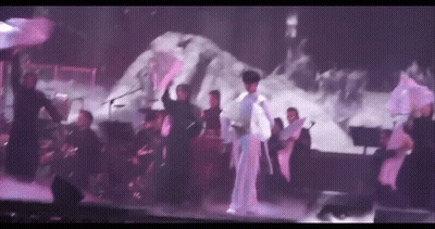A Group Of People Are Dancing On A Stage While A Man Sings . GIF