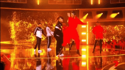 A Group Of People Are Dancing On A Stage With A Crowd Watching . GIF