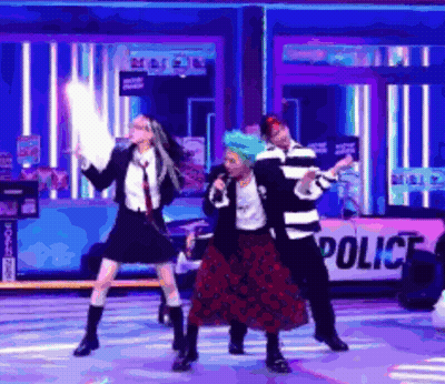A Group Of People Are Dancing On A Stage With A Police Sign In The Background . GIF