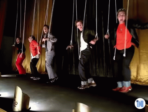 A Group Of People Are Dancing On A Stage With The Letter N Behind Them GIF