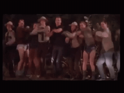A Group Of People Are Dancing Together On A Stage In A Dark Room . GIF