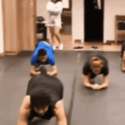 A Group Of People Are Doing Push Ups On The Floor . GIF