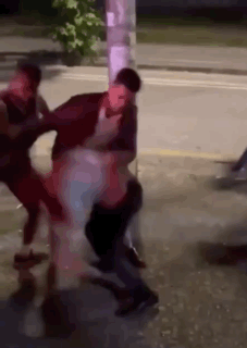 A Group Of People Are Fighting On The Side Of A Street . GIF