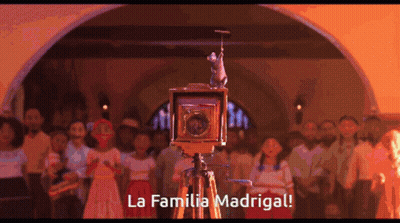 A Group Of People Are Gathered Around A Camera That Says La Familia Madrigal On It GIF