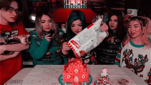 A Group Of People Are Gathered Around A Gingerbread House And One Of The Girls Is Holding A Bag Of Kraft Macaroni And Ch GIF
