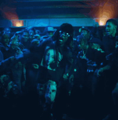A Group Of People Are Gathered In A Dark Room With A Man Wearing A Shirt That Says ' Bb ' GIF